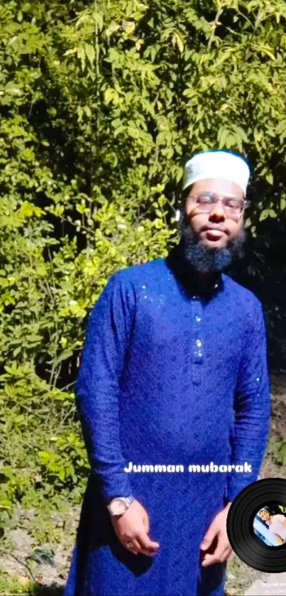 Man in blue attire with green background celebrating Jumma Mubarak.