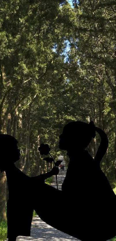 Silhouette of two figures on a forest path, surrounded by tall green trees.