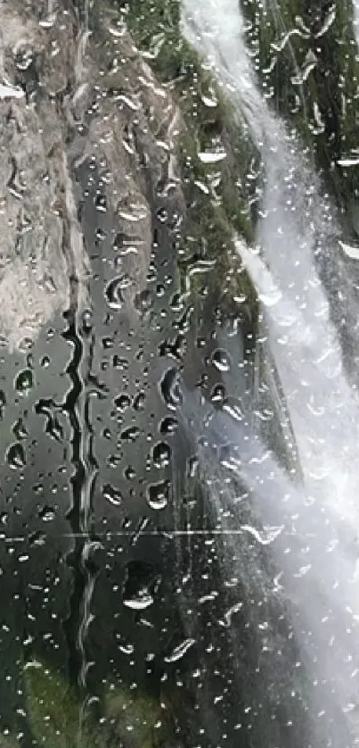 Raindrops on glass with waterfall view, creating a serene and natural mobile wallpaper.