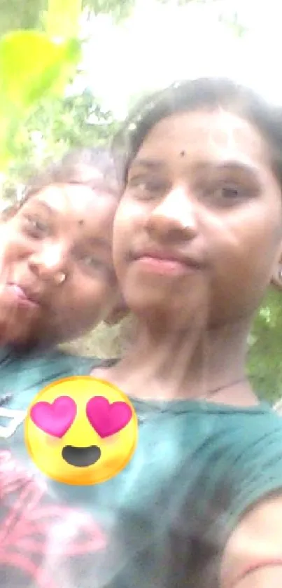 Friends taking a joyful selfie outdoors with green leaves.