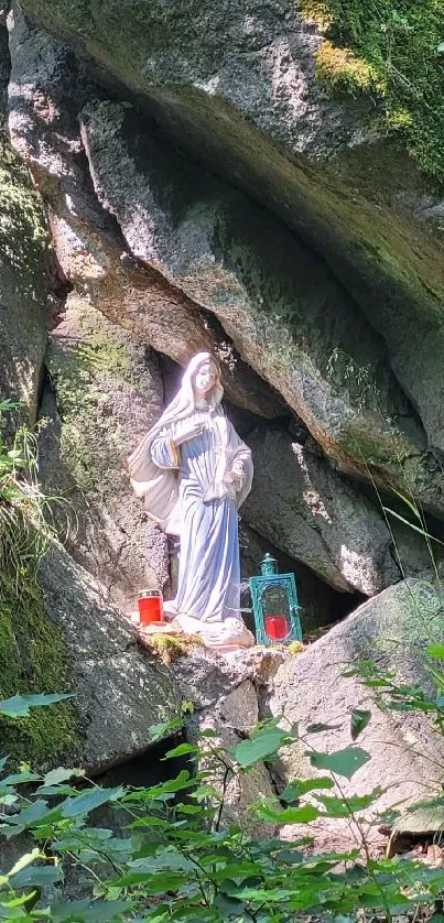 Statue nestled in a lush forest setting with rocky backdrop and greenery.