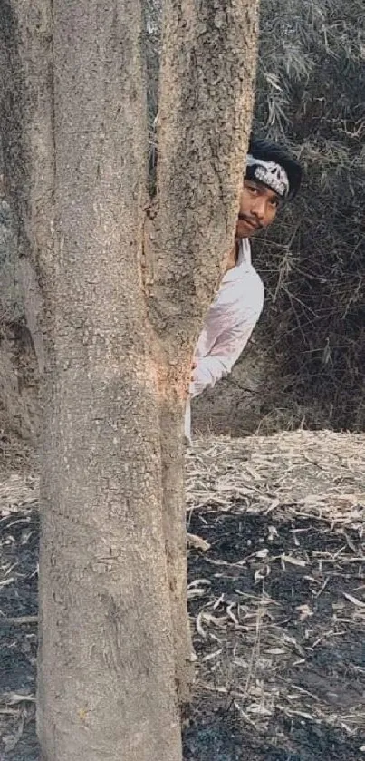 Person peeking from behind a tree in a natural setting wallpaper.