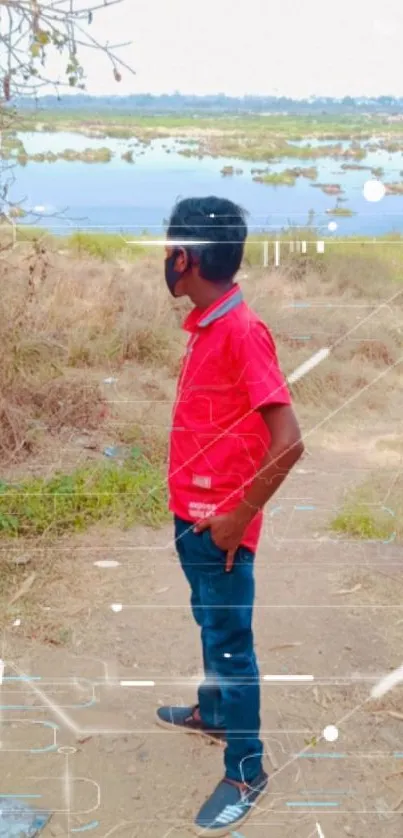 Person in red shirt by riverside with blue sky backdrop.