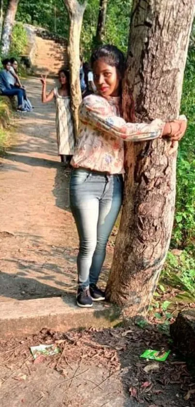 Person hugging a tree on a sunlit forest trail.