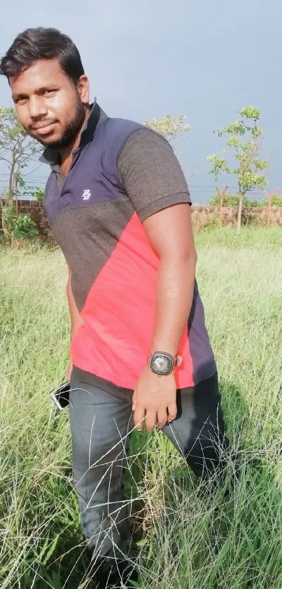 Man standing in green field under bright sky.