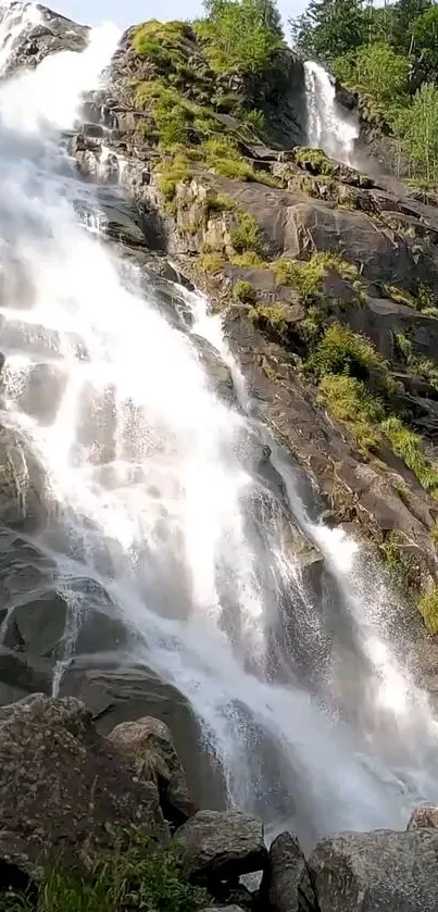 Cascading waterfall with rocks and greenery, perfect for mobile wallpaper.