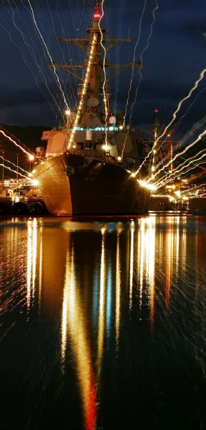 Navy ship docked at a night harbor with vibrant reflections on water.