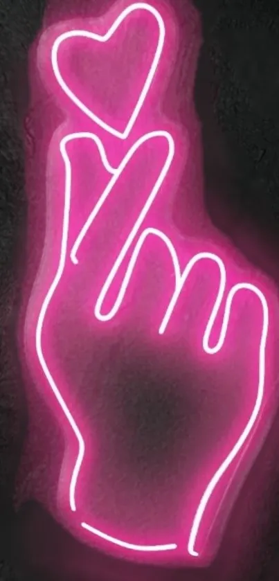 Pink neon hand with heart on dark background.