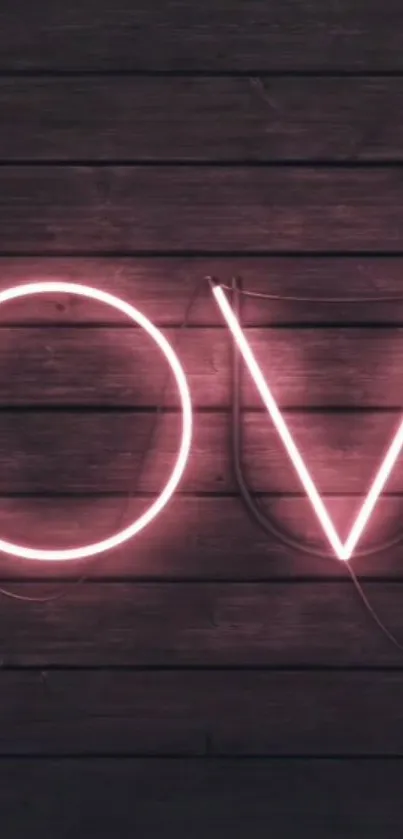 Neon love sign on dark wooden background with pink glow.