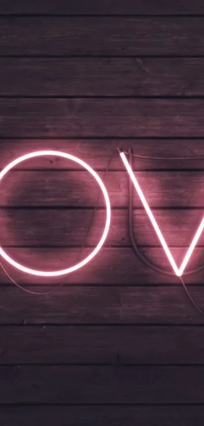 Neon love sign glowing against dark wooden background.