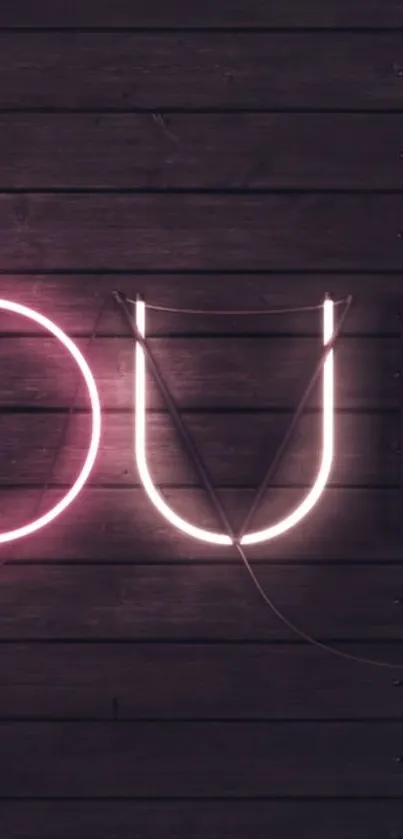 Neon love displayed on dark wood background with pink lighting.