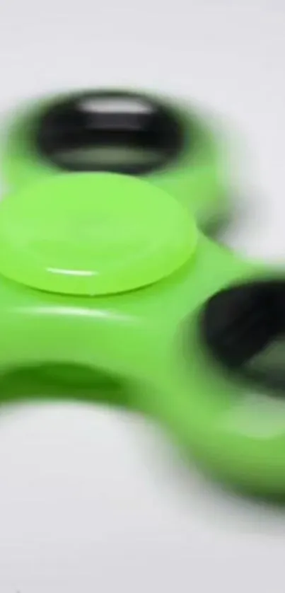 Neon green fidget spinner on a blurred background.