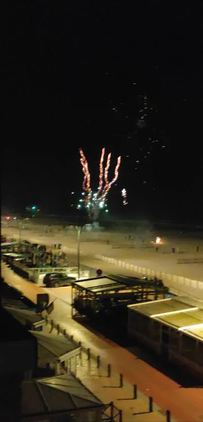 Fireworks illuminate the night sky over a serene beach.