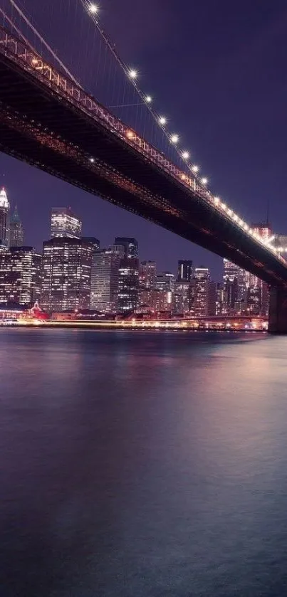 Nighttime view of a city with a lit bridge over water, reflecting lights.