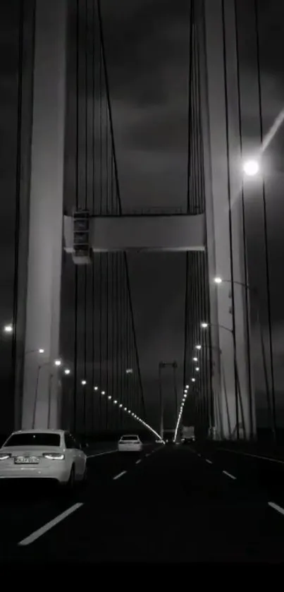 Monochrome night view of a suspension bridge with glowing lights.