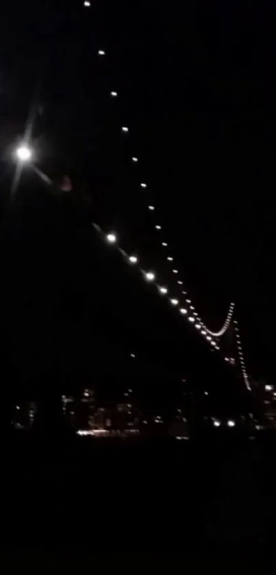 Illuminated bridge lights against cityscape at night.