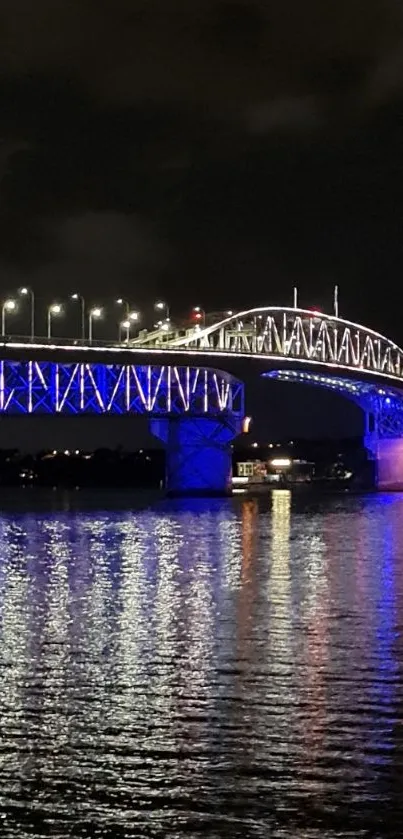 A stunning night scene of a bridge lit in blue, reflecting on calm waters.