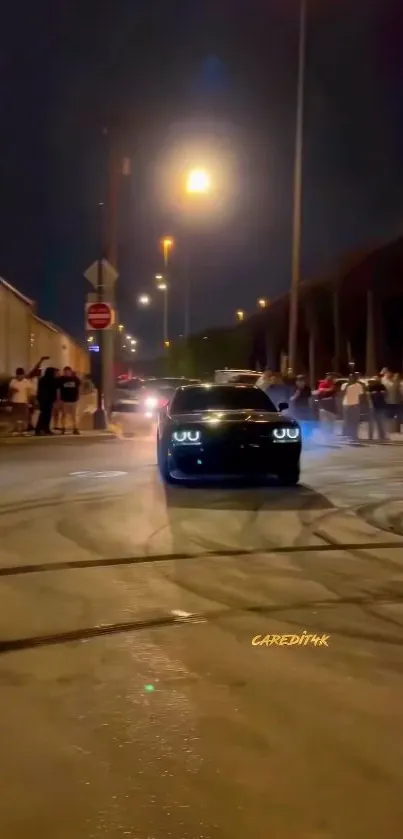 Black car with glowing headlights in a night street scene.