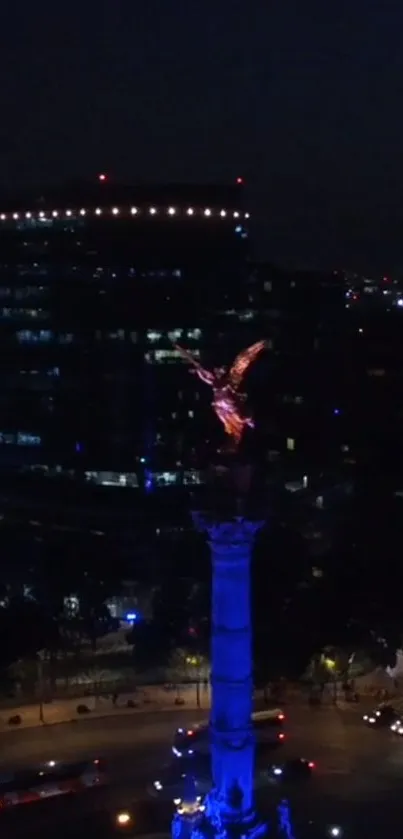 Illuminated angel statue against a nighttime cityscape.