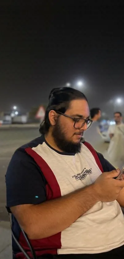 A man using a phone with a night cityscape background.