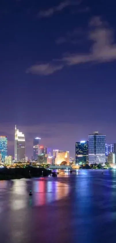 Night skyline with city lights reflecting on water.