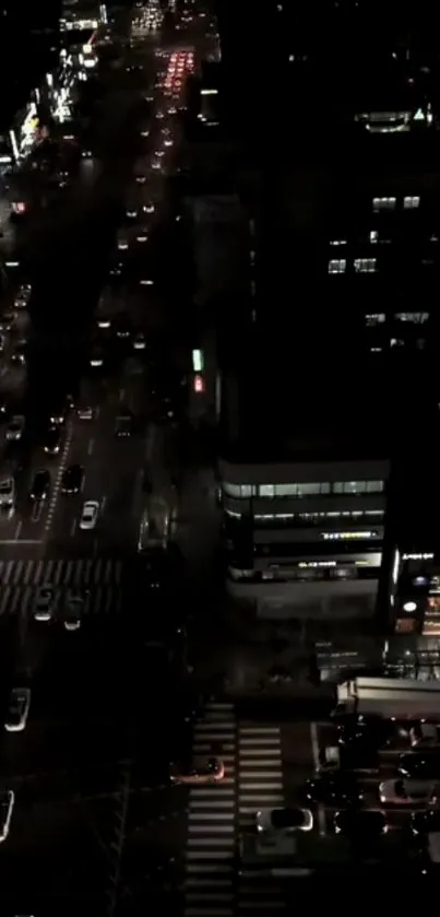 Aerial nighttime view of a city street with lights and moving cars.