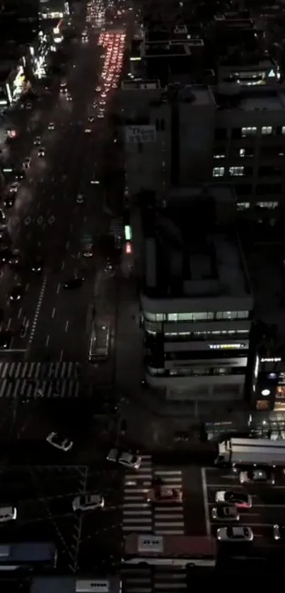 A city street at night with glowing lights and traffic, viewed from above.