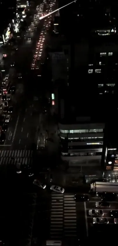 Aerial view of a city street at night with glowing lights and traffic.