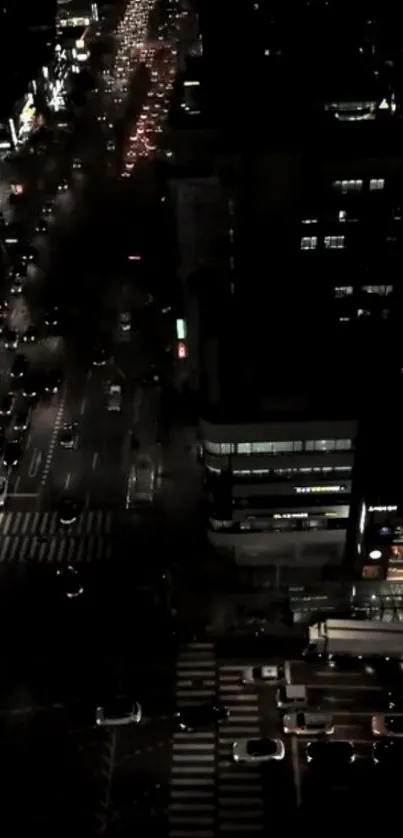 Aerial view of city streets at night with glowing lights and busy traffic.