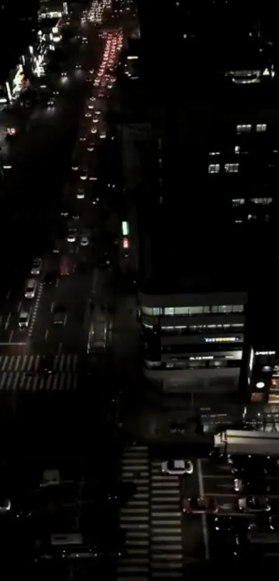 Aerial night view of city streets with traffic and illuminated buildings.