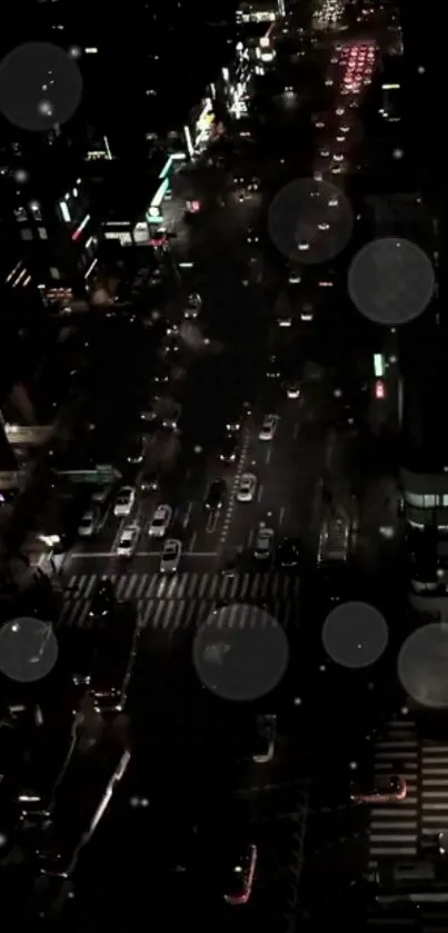 Aerial view of city streets at night with glowing lights and traffic movement.