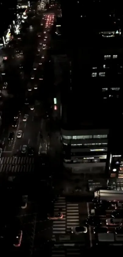 Aerial view of a busy city street at night with glowing lights and traffic.