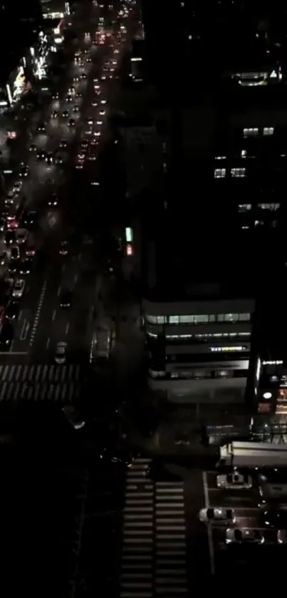 Aerial view of city street at night with vibrant traffic lights.