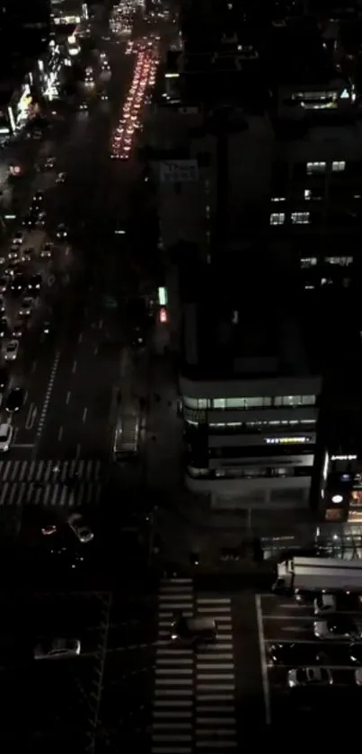 Aerial night view of city street with traffic and glowing lights.