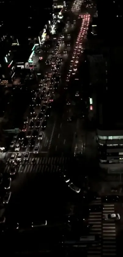 Aerial view of city street traffic at night with glowing lights and urban scenery.