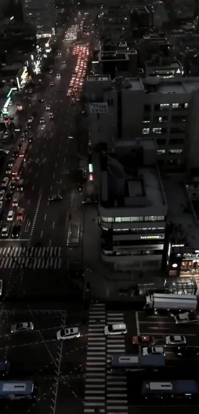 Aerial view of city streets at night with bright lights and dark buildings.