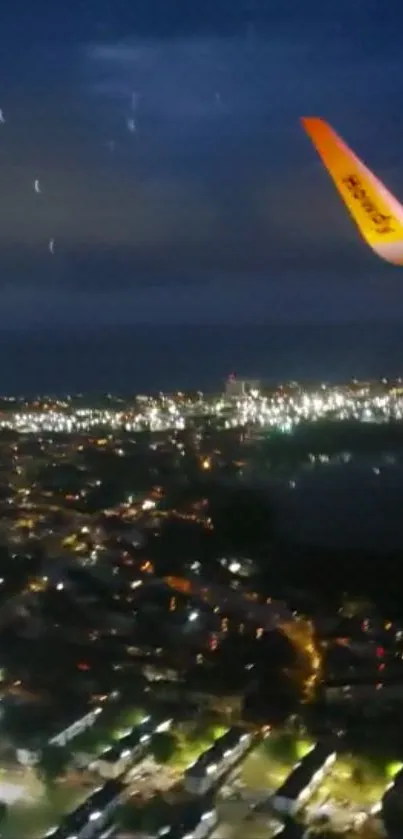 Aerial view of a city at night with airplane wing.