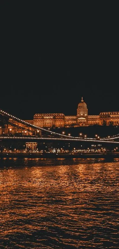 Illuminated bridge and cityscape at night with reflections on water.