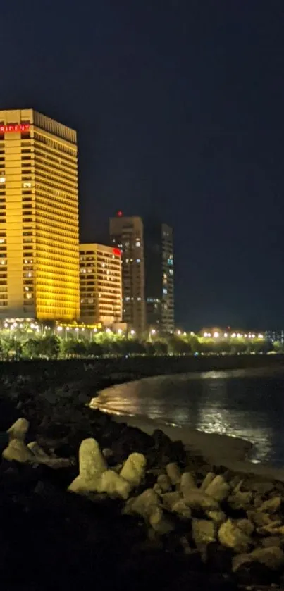 Cityscape at night featuring lit buildings by the water.