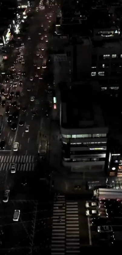 An aerial night view of a city's bustling streets illuminated by city lights.