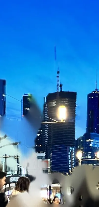 Night cityscape with skyscrapers illuminated against a blue sky.