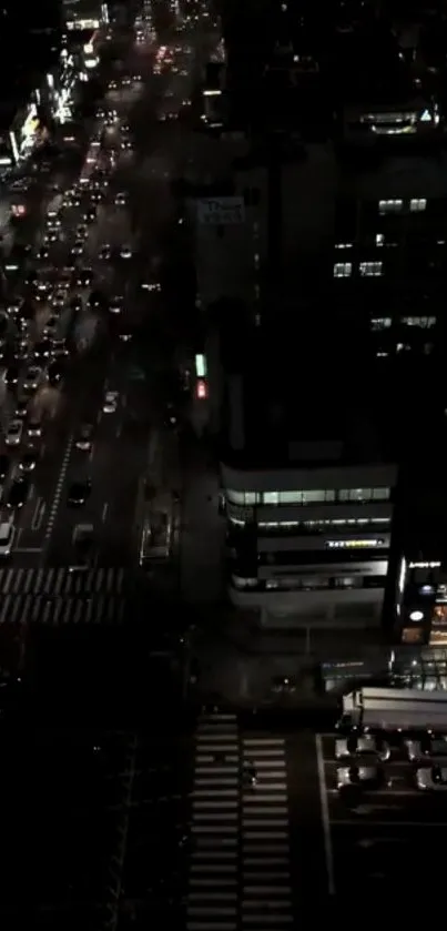 Aerial view of a city street at night with busy traffic and glowing lights.