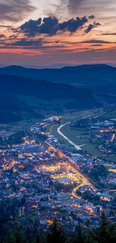 A cityscape illuminated at dusk with a darkening sky and mountain outlines.