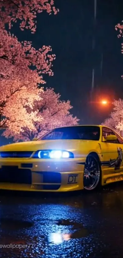 Yellow sports car under cherry blossoms at night.