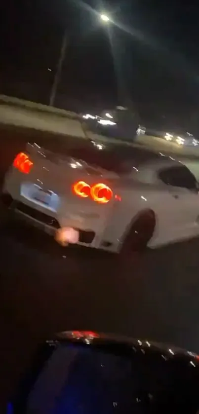 Sleek white sports car driving at night on a dimly lit highway.