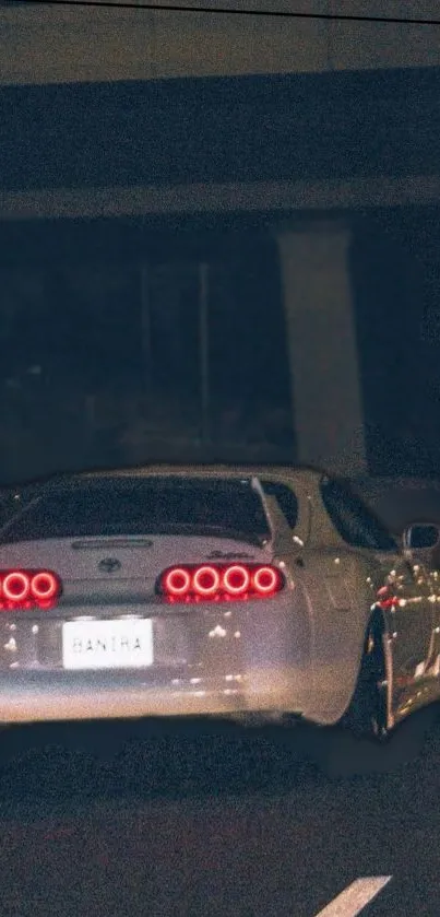 Rear view of a sports car driving through a dimly lit road at night.