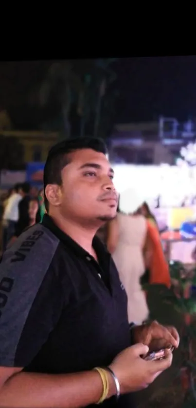 Man at a night event with blurred vibrant background.