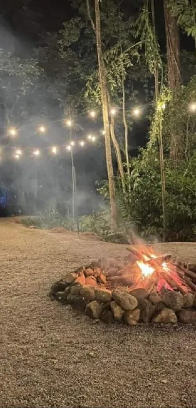 Campfire glowing under string lights in a peaceful forest setting at night.