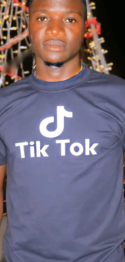 Person wearing a TikTok-themed black t-shirt at night.