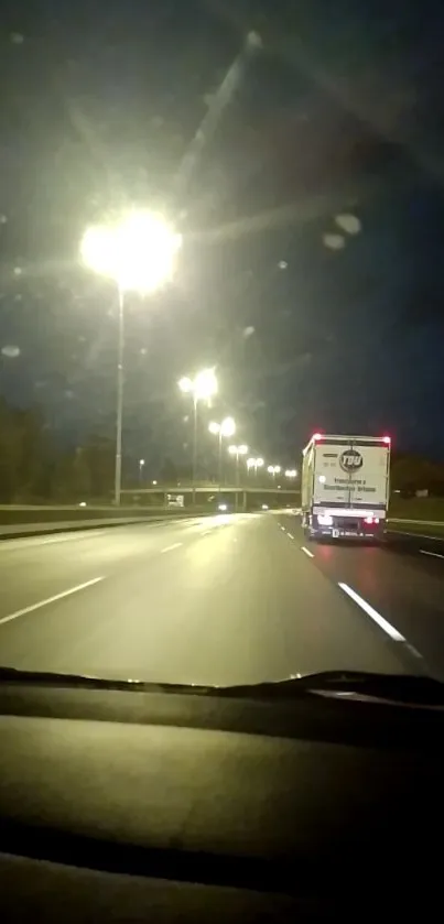 Nighttime highway with glowing streetlights and a distant moving truck.